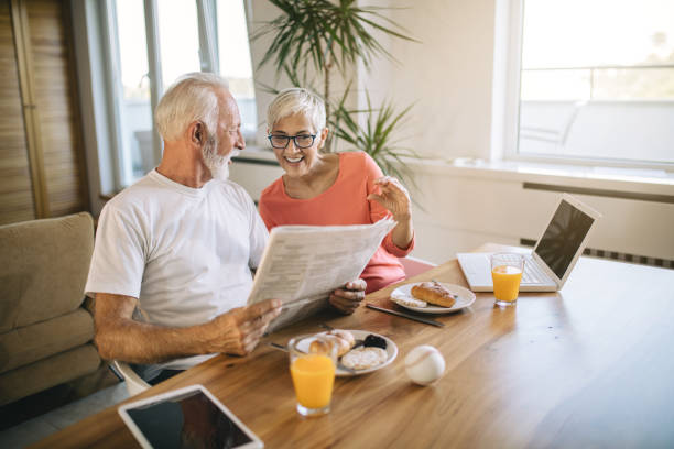 istock Beautiful senior couple reading newspaper while enjoying a breakfast 1055662714