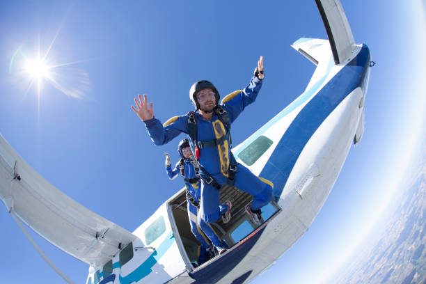 Skydivers fall towards earth Plane and sky behind fish eye effect stock pictures, royalty-free photos & images