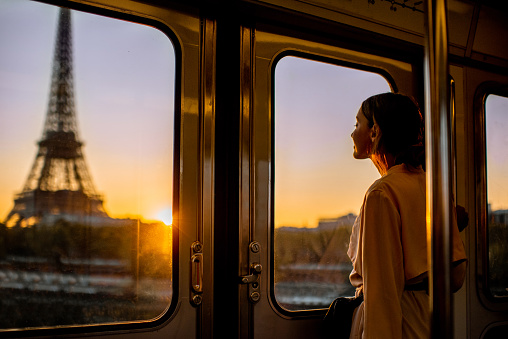 Young woman enjoying view on the Eiffel tower from the subway train during the sunrise in Paris