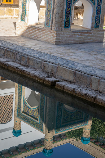 Reflection of shrine in pool at the Mausoleum of Bahouddin Nakshband, or Bakhuddin Nakshbandi, founder of Sufism in Bukhara, Uzbekistan.