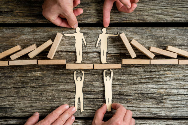 istock Business teamwork and cooperation concept with the hands of four businesspeople supporting paper cut outs 1055683098