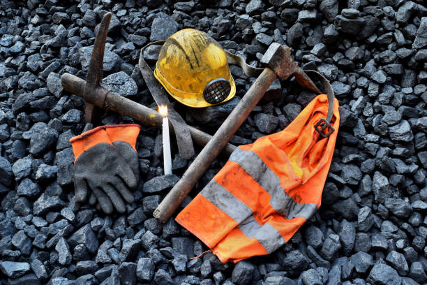 istock Vigil light, candle with the miner belongings (helmet, gloves, pickaxe, vest, belt) 1055692096