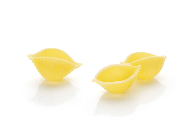 istock Raw yellow pasta conchiglie isolated on white 1055705010