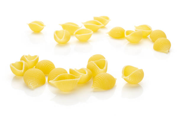istock Raw yellow pasta conchiglie isolated on white 1055705022