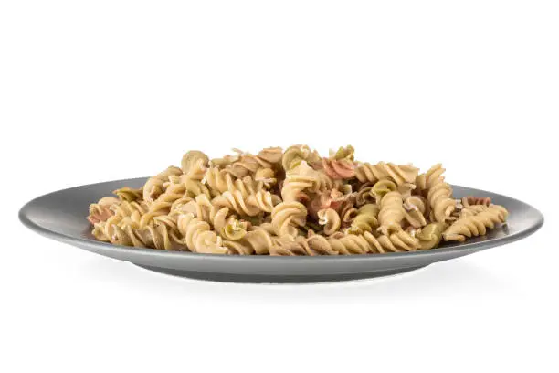 Lot of whole raw pasta fusilli variety on grey ceramic plate isolated on white background