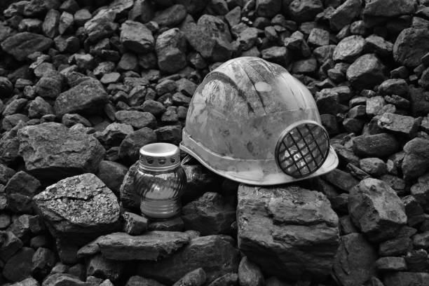 istock Lighted vigil light candle with the miner belongings (helmet, gloves, pickaxe, shovel, vest, belt) 1055709676