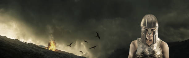 istock Strong gladiator warrior with metal armor in front of bonfire and stormy clouds 1055716832