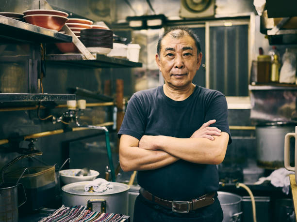 Japanese Ramen Shop Owner The owner of a small ramen shop in Tokyo, Japan standing in the kitchen of his restaurant. japanese chef stock pictures, royalty-free photos & images