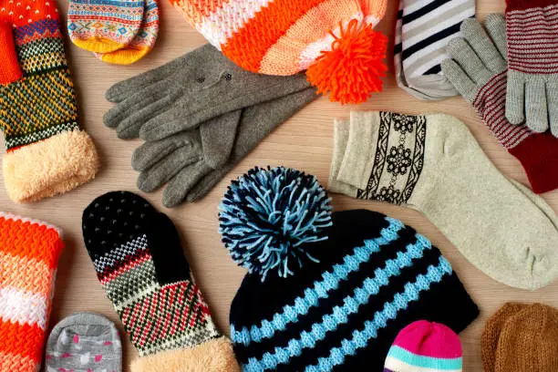 Caps, mittens, gloves and socks for cold seasons. Warm autumn and winter clothes. View from above.