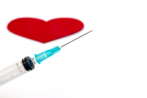 istock Syringe close up with red heart on white background 1055867032
