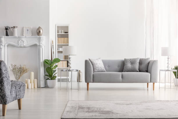 istock Lamp on table next to grey settee in white loft interior with armchair and copy space. Real photo 1055867338
