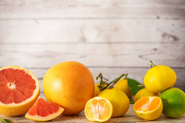 istock Fresh grapefruits and citrus fruits on light wooden table. With copy space 1055867900