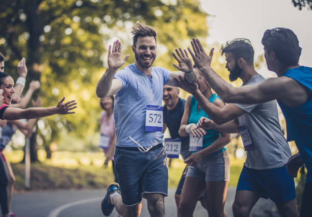 幸せなマラソン ランナー挨拶グループ フィニッシュ ラインでの選手の。 - marathon running group of people jogging ストックフォトと画像