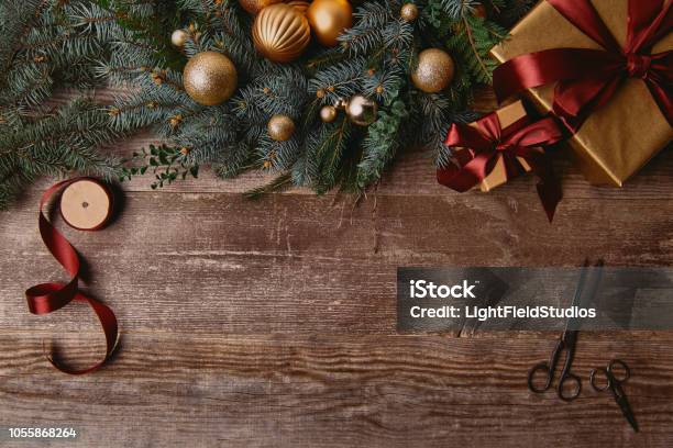 Top View Of Christmas Gift Boxes Fir Wreath Ribbon Spool And Scissors On Wooden Table Stock Photo - Download Image Now