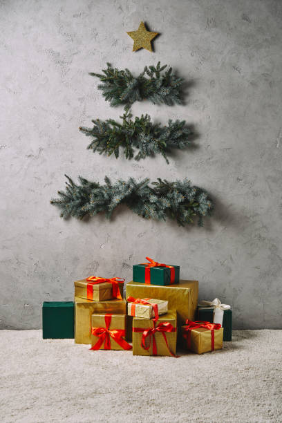 istock handmade Christmas tree hanging on grey wall, gift boxes on carpet in room 1055868582
