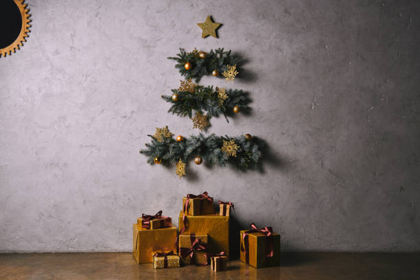 istock handmade Christmas tree hanging on grey wall, gift boxes on floor in room 1055868626