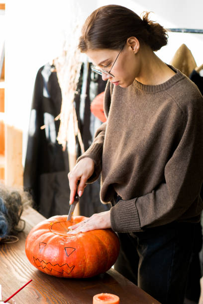 istock Serious craftswoman cutting pumpkin lid 1055874314