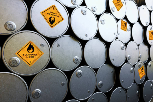 uma pilha de barris de petróleo metálico brilhante com "líquido inflamável" aviso sigs - flammable - fotografias e filmes do acervo