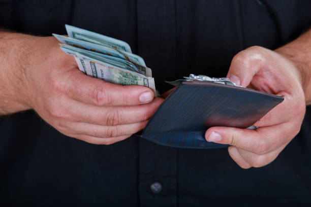 istock Leather wallet with money in male hands on dark background 1055876562