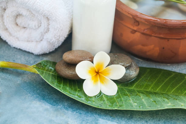 istock Spa objects and stones for massage treatment with flower and green leave on blue background. 1055877216