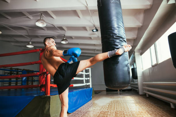 istock Male boxer workout high kick on the punching bag in gym 1055879646