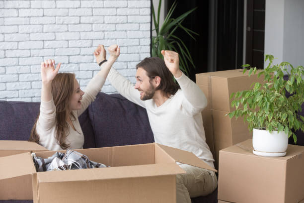 istock Couple sitting on couch in living room with cardboard boxes 1055880356