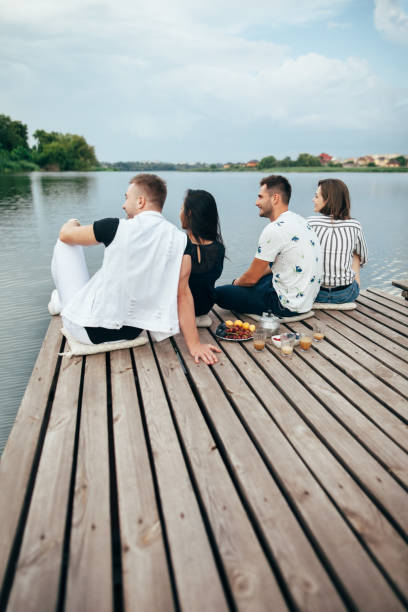 istock Back view of friends relaxing on river pier 1055880540
