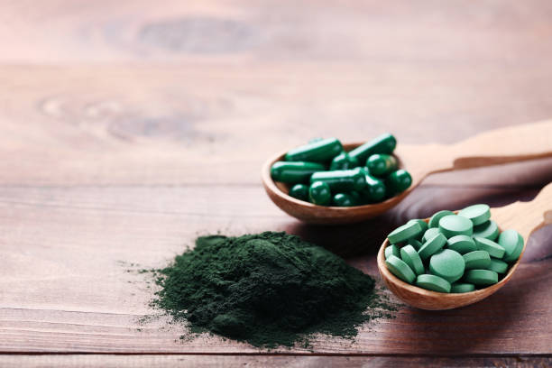 spirulina 가루와 갈색 나무 테이블에 숟가락에 정제 - spirulina bacterium green vitamin pill medicine 뉴스 사진 이미지