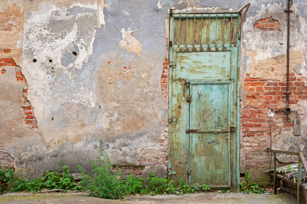 istock grunge metal door, cracked red brick wall 1055884476