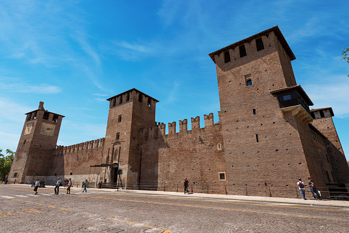 Verona, Veneto, Italy - May 13th, 2013: Castelvecchio - The medieval old castle (Scaligero) in Verona (UNESCO world heritage site) - Veneto, Italy, Europe. It is the most important military construction of the Scaliger dynasty that ruled the city in the Middle Ages. Tourists and locals stroll in front of the ancient monument. Castelvecchio is now home to the Castelvecchio Museum and the local officer's club which can be accessed through the left door on Corso Cavour.