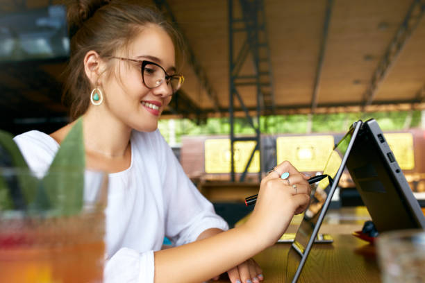 Freelancer mixed race woman hand pointing with stylus on convertible laptop screen in tent mode. Asian caucasian girl using 2 in 1 notebook with touchscreen for drawing and work on design project. Freelancer mixed race woman hand pointing with stylus on convertible laptop screen in tent mode. Asian caucasian girl using 2 in 1 notebook with touchscreen for drawing and work on design project. Creative artist technology. hybrid vehicle stock pictures, royalty-free photos & images