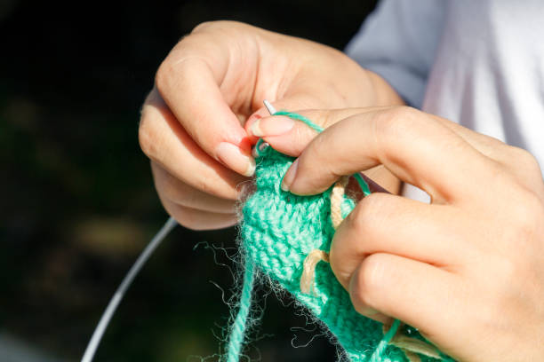 istock woman knits clothes from wool with knitting needles 1055888892