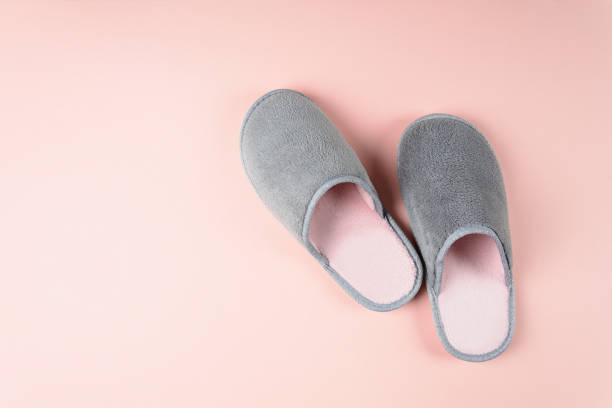 Gray and pink home slippers on a pastel paper background. Top view. Copy space Gray and pink home slippers on a pastel paper background. Top view. Copy space slipper stock pictures, royalty-free photos & images