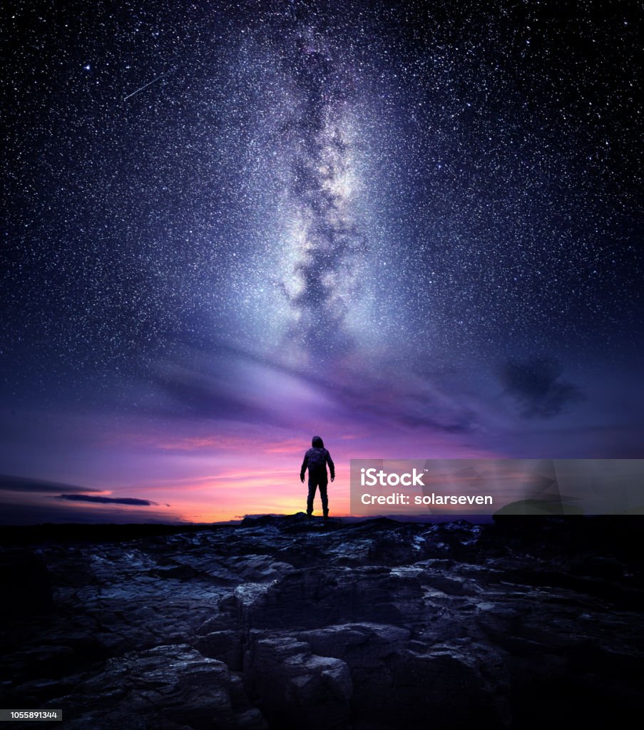 Milky Way Galaxy Night Landscape Night time long exposure landscape photography. A man standing in a high place looking up in wonder to the Milky Way galaxy, photo composite. Outer Space Stock Photo