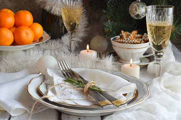istock Christmas And New Year Holiday Table Setting. Celebration. Place setting for Xmas Dinner. Holiday Decorations. Decor. Plate, Tangerines, Glasses With Champagne, Fruit cake 1055891568