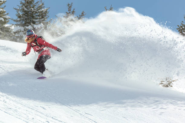 Female snowboarder riding on powder snow