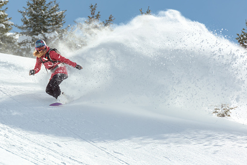 Female snowboarder riding on powder snow