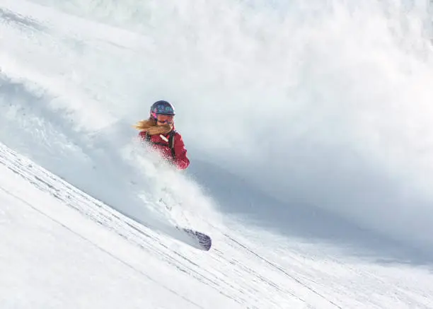 Female snowboard rider riding on fresh powder snow
