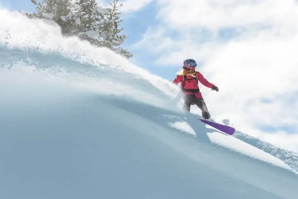 Female snowboard rider making a turn on deep powder snow