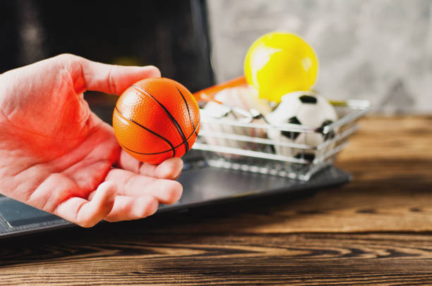 main de l’homme tient le ballon sur fond de panier et vieux portable sale sur la table en bois brun. concept de commerce en ligne - business human foot shoe men photos et images de collection