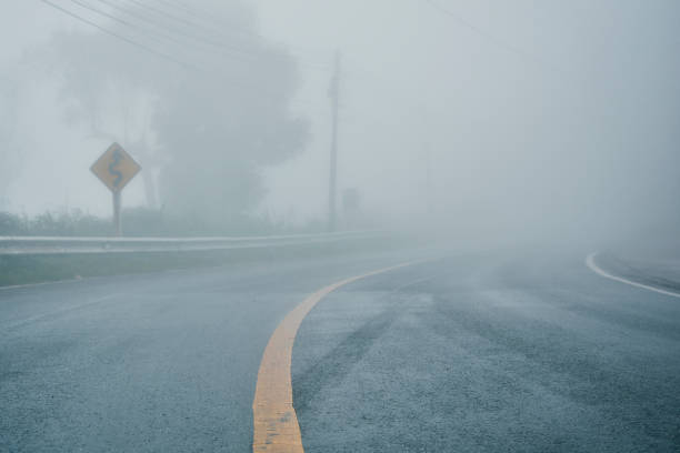 Photo of foggy rural asphalt highway perspective with white line, misty road, Road with traffic and heavy fog, bad weather driving