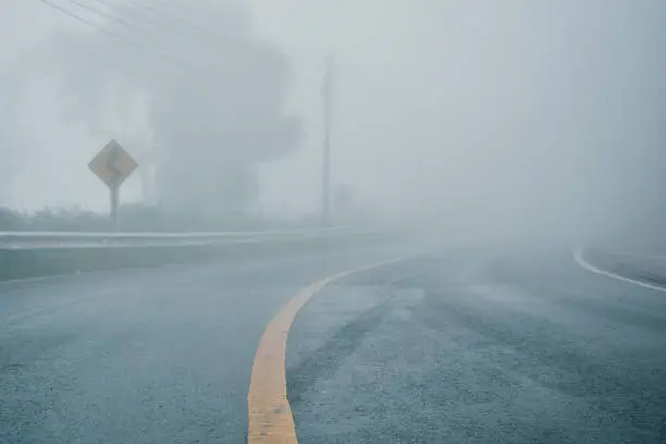 Photo of foggy rural asphalt highway perspective with white line, misty road, Road with traffic and heavy fog, bad weather driving