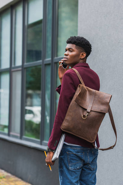 istock handsome young student with leather backpack talking by phone on street 1055909824