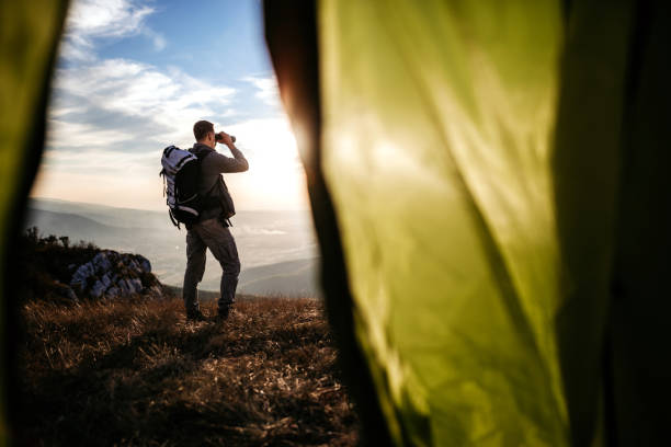 istock Man explorer with a tent at top of mountain 1055910418
