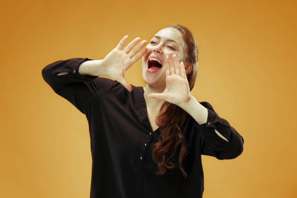 istock Isolated on orange young casual woman shouting at studio 1055911500