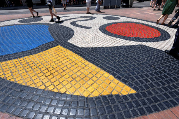 Barcelona, Spain - June 13, 2014: Mosaic del Pla de l'Os by Joan Miro in the middle of the Rambla, the most important road in Barcelona, Catalonia, Spain. Tourists and locals stroll in the downtown. Joan Miró i Ferrà was a Spanish painter, sculptor, and ceramicist born in Barcelona.