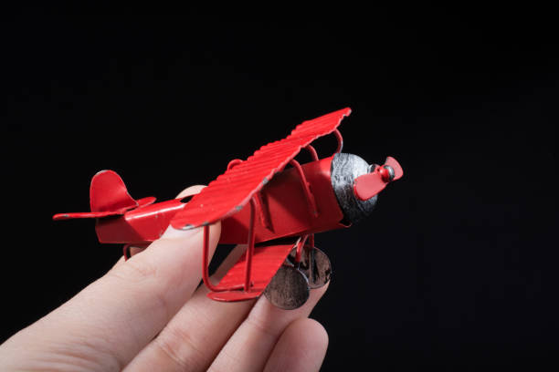 istock Hand holding a toy plane on black background 1055914788