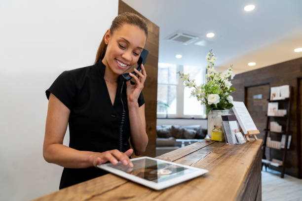 mujer que trabaja en un spa de hablar por teléfono - hotel reception fotografías e imágenes de stock