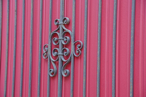 texture of black steel rods and forged pattern on a fragment of a red metal wall