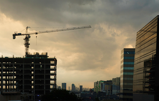 Central Jakarta aerial skyline construction site and stormy sunset,  featuring the rapidly growing downtown area rising above trees.